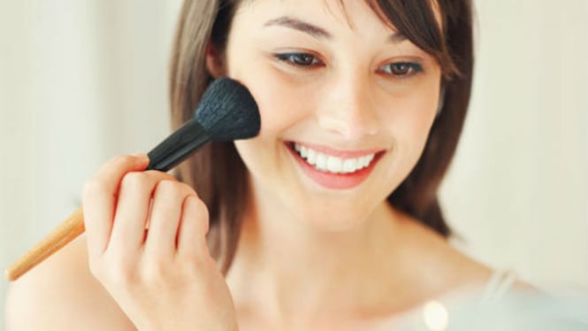 Wanita memakai blush on.